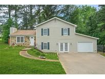 Two-story home featuring light siding, stone accents, attached garage, and a well-manicured front lawn at 2959 Pritchards Mill Trl, Douglasville, GA 30135
