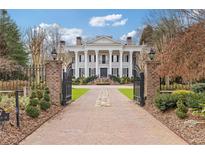 Elegant gated estate with a grand facade, stately columns, and a brick driveway leading to a luxurious home at 3977 Sweet Bottom Dr, Duluth, GA 30096
