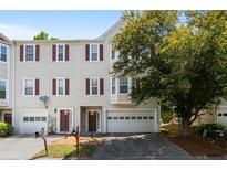 Traditional townhome featuring red shutters, mature landscaping, and attached one-car garage at 2061 Pinnacle Pointe Dr, Norcross, GA 30071