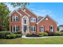 Beautiful two-story brick home with a well-manicured lawn, garden and mature landscaping at 2330 Springmonte Pl, Cumming, GA 30041