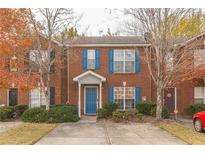 Charming brick townhome with blue shutters and door, complemented by mature landscaping and a concrete driveway at 3151 Kingswood Gln, Decatur, GA 30034