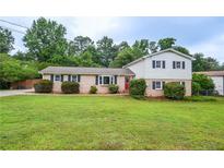 Charming two-story home featuring a lush green lawn and mature landscaping at 456 Harmony Grove Rd, Lilburn, GA 30047