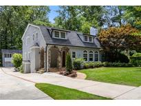 Charming two-story home featuring a stone-arched entry, a well-manicured lawn, and mature trees at 1195 Cameron Ct, Atlanta, GA 30306