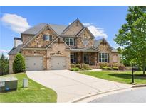 Charming stone and brick home with a two-car garage and well-manicured lawn at 5075 Havenbrooke Ct, Cumming, GA 30040