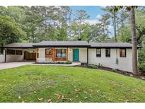 Charming renovated home with white painted brick and a teal front door, nestled on a lush, tree-filled lot at 3356 Thornewood Dr, Atlanta, GA 30340