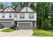 Charming gray two-story townhouse with a one car garage, manicured lawn and a concrete driveway at 153 Witter Way, Woodstock, GA 30188