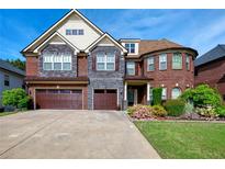Elegant brick and stone home featuring a three-car garage, manicured lawn, and beautiful landscaping at 3642 Lake Estates Way Way, Atlanta, GA 30349