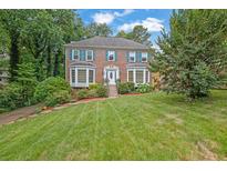 Charming two-story brick home featuring a well-manicured lawn, mature trees, and colorful flower beds at 3897 Tanbark Ct, Marietta, GA 30066