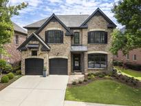Charming two-story brick home with a well-manicured lawn and black trim and two-car garage at 570 Society St, Alpharetta, GA 30022