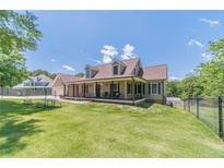 Charming home featuring a long porch, fenced yard, dormer windows, and lush green lawn and professional landscaping at 3040 Sandy Creek Ct, Loganville, GA 30052