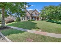 Charming two-story brick home with a lush, green lawn and mature trees at 3451 Falls Branch Ct, Buford, GA 30519