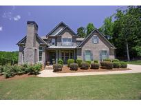 Charming two-story brick home with a lush, landscaped front yard and a welcoming front porch at 1231 Fawndale Nw Dr, Kennesaw, GA 30152