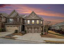 Beautiful two-story brick home featuring a two-car garage and a well-maintained front yard against a colorful sunset sky at 5621 Cobblestone Creek Ave # 14, Mableton, GA 30126