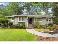 Charming brick home with landscaped front yard, stone pathway, and stairs leading to the front door at 2180 Howell Mill Nw Rd, Atlanta, GA 30318