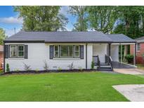 Charming, updated home with white brick, dark shutters, covered carport, and fresh landscaping at 1398 Woodland Ave, Atlanta, GA 30316