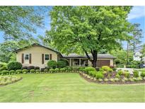 Charming home featuring a lush front yard with manicured landscaping and mature trees, creating inviting curb appeal at 733 Huntington Se Pl, Marietta, GA 30067