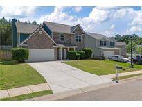 Charming two-story home with brick accents, a well-manicured lawn, and a spacious driveway at 211 Augusta Woods Dr, Villa Rica, GA 30180