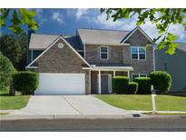 Charming two-story home featuring a stone facade, well-manicured lawn, and a two-car garage at 211 Augusta Woods Dr, Villa Rica, GA 30180