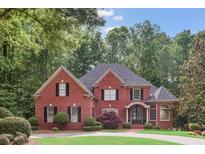 Elegant red brick home featuring a manicured lawn and lush landscaping, offering a charming curb appeal at 63 Lewellen Dr, Marietta, GA 30064