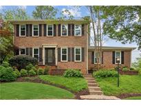 Charming two-story brick home with black shutters and a beautifully landscaped front yard at 9800 Woodfall Dr, Roswell, GA 30076