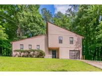 Charming home featuring a manicured lawn, tall trees, a garage, and a unique architectural design at 3851 Natalie Way, Ellenwood, GA 30294