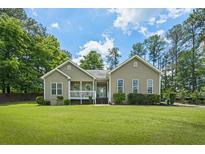 Charming one-story home with a covered front porch, lush lawn, and mature trees at 380 Russell Rd, Lawrenceville, GA 30043