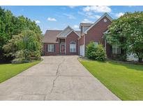 Brick home featuring a long driveway, a manicured lawn and mature landscaping at 4591 Millstone Walk Ne Dr, Buford, GA 30519