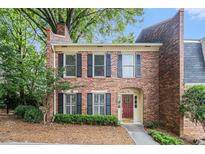 Charming brick townhome with black shutters, a red door, and lush landscaping at 6 Stratford Hall Ne Pl, Atlanta, GA 30342