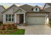 Charming single-Gathering home featuring brick facade, manicured landscaping, and attached two-car garage at 209 Floral Valley Dr, Woodstock, GA 30188