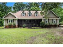 Charming home featuring a well-manicured lawn, inviting screened-in porch, and classic architectural details at 324 Kibbee Rd, Mcdonough, GA 30252