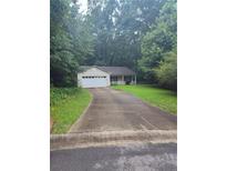 Charming single-story home with a front porch, attached garage, and a long driveway surrounded by lush greenery at 10073 Dorothy Ct, Jonesboro, GA 30236