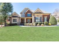 Charming two-story home with brick and stone accents, manicured lawn, and mature trees at 5352 Lacosta Ln, Alpharetta, GA 30022