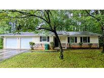 Charming ranch-style home featuring a stone accent wall, a well-manicured lawn, and a convenient two-car garage at 5517 Green Wing Ct, Lithonia, GA 30058