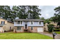 Split-level home boasts stone accents, a front porch, attached garage, and a well-manicured front lawn at 2168 Sara Ashley Way, Lithonia, GA 30058