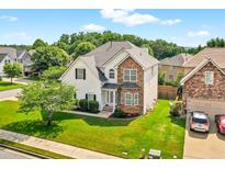 Charming two-story home featuring a well-manicured lawn, stone accents, and lush landscaping at 910 Pebble Creek Trl, Suwanee, GA 30024
