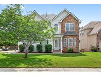Charming two-story home featuring a combination of stone and siding with a well-manicured front lawn and mature tree at 910 Pebble Creek Trl, Suwanee, GA 30024