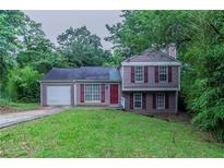 Charming two-story home featuring red shutters, a red door, green grass, and mature trees in a suburban setting at 4634 Garden Hills Dr, Stone Mountain, GA 30083