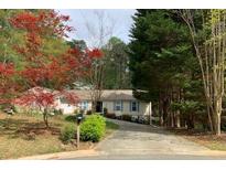 Charming single-story home with a well-manicured lawn, mature trees, and a driveway leading to the front entrance at 1185 Wedgefield Sw Dr, Marietta, GA 30064