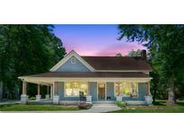 Charming blue home with a covered front porch and a beautiful dusk sky in the background at 1382 6Th Ave, Auburn, GA 30011
