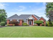 Charming brick home with lush lawn, manicured landscaping, and mature trees at 411 Hickory Fairway Ct, Woodstock, GA 30188