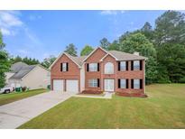 Charming two-story brick home with a well-maintained lawn and a two-car garage at 1486 Rogers Crossing Dr, Lithonia, GA 30058