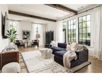 Bright living room featuring large windows, a dark sectional sofa, and exposed beams on the ceiling at 77 Delmont Ne Dr, Atlanta, GA 30305