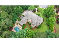 Stunning aerial view of estate home with a backyard pool, lush landscaping, and mature trees at 816 Blackfoot Trl, Suwanee, GA 30024