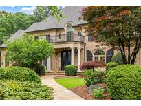 Beautiful brick home featuring a stone walkway, manicured landscaping, a second story balcony, and an iron front door at 816 Blackfoot Trl, Suwanee, GA 30024