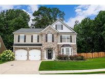 Charming two-story home features a stone facade, manicured lawn, and a two-car garage at 3395 The Commons Dr, Cumming, GA 30041
