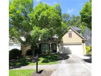 Charming home with a well-manicured lawn, mature trees, and a two-car garage on a sunny day at 942 Idlewood Dr, Canton, GA 30115