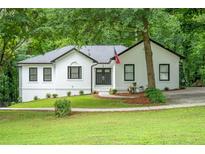 Charming white home with black trim and lush green lawn and mature trees at 3924 Ashford Dunwoody Road Northeast Ne Rd, Atlanta, GA 30319
