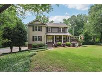 Charming two-story home with a welcoming front porch and lush green lawn surrounded by mature trees at 10875 Shagbark Trl, Roswell, GA 30075