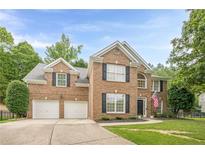 Charming two-story brick home featuring a two-car garage and manicured landscaping for a warm, inviting curb appeal at 1245 Mountain Ivey Ct, Sugar Hill, GA 30518