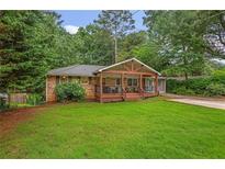 Charming brick home featuring a welcoming front porch and lush green lawn at 3510 Dunn Se St, Smyrna, GA 30080